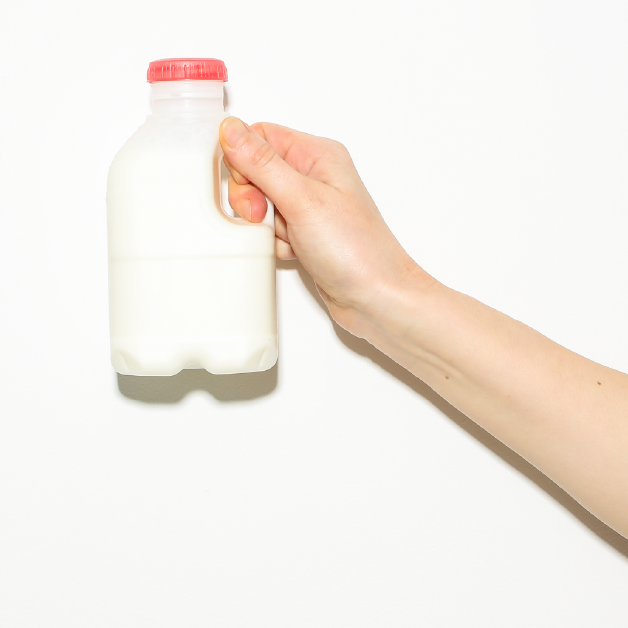 Holding up milk bottle Person holding up a milk bottle